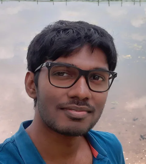 Vasanth smiling, with a still lake behind him